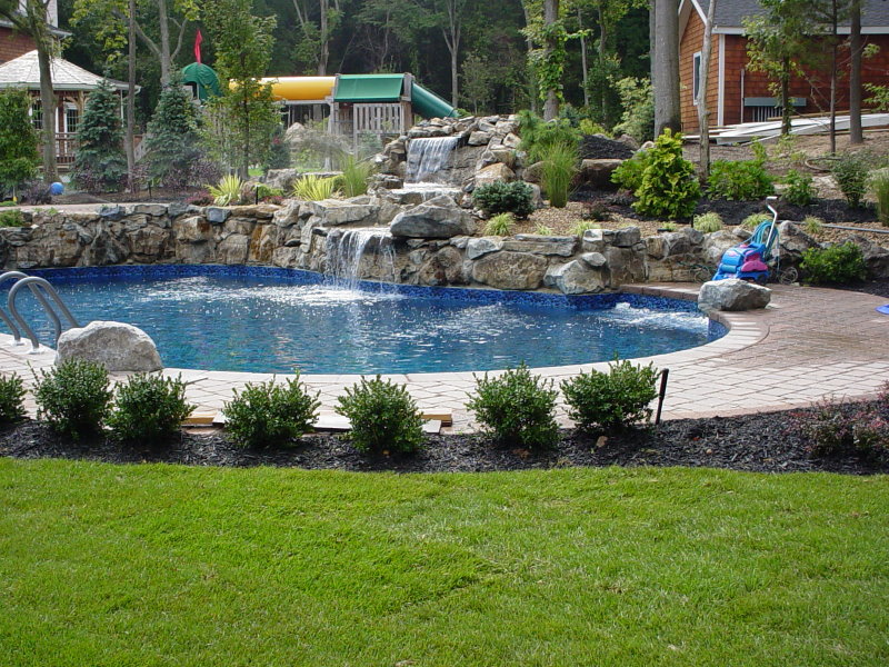 large scale moss rock water feature into pool